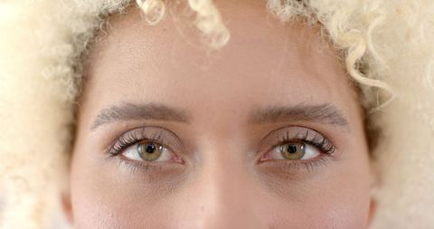 Close-up of biracial woman's eyes with curly blonde hair