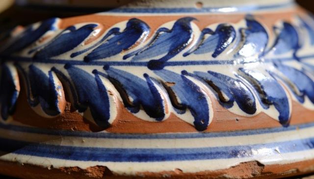 Macro detail of cobalt leaf glazed terracotta band on handcrafted ceramic vessel with raised pattern