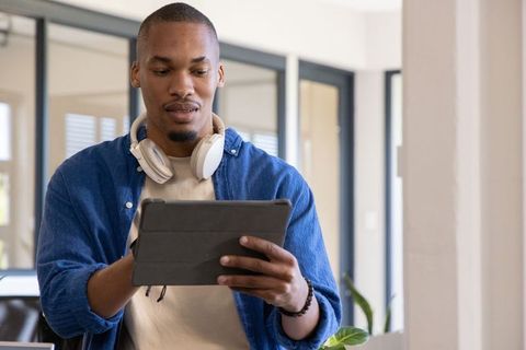 African american man using tablet with headphones in modern minimalist office