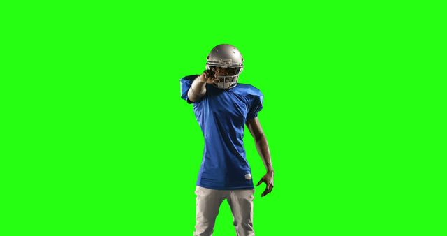 American football player is pointing forward with a confident pose. He is wearing a helmet and sports uniform with a green screen background, making it easy to alter the background. Perfect for sports promotions, motivational posters, athletic advertisements, and visual effects projects.