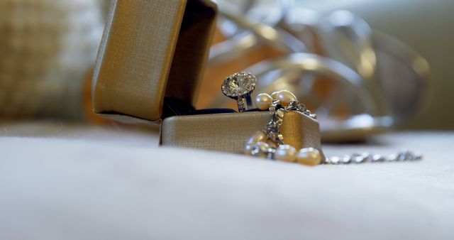 Close up of wedding ring in box with pearl necklace on pillow. Wedding, celebration and jewellery.