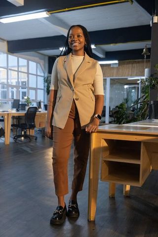 Confident african american woman standing smiling in modern coworking office with smartwatch