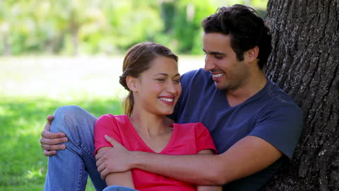 Joyful Couple Embracing Under Tree in Sunny Park
