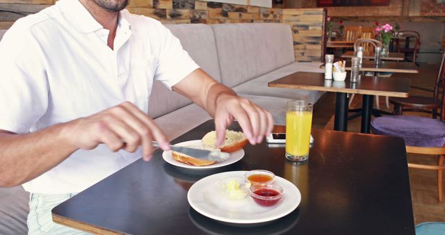 Man Spreading Butter on Toast in Café with Beverage on Table - Download Free Stock Images Pikwizard.com