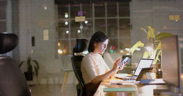 Businesswoman Working Late in Modern Office Using Smartphone and Laptop - Download Free Stock Images Pikwizard.com