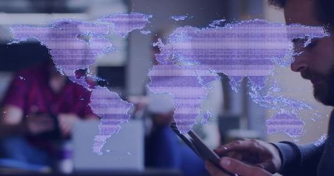 Bearded man tapping tablet while holographic world map overlaying co-working lounge