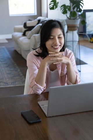 Smiling Woman Using Laptop in Cozy Living Space