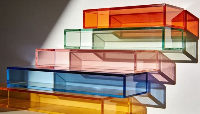 Stacked translucent acrylic trays casting colorful geometric shadows on white backdrop