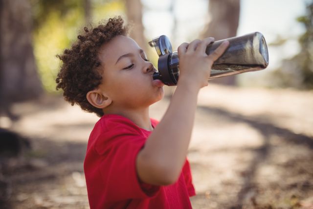 Boy drinking water after workout during obstacle course in boot camp