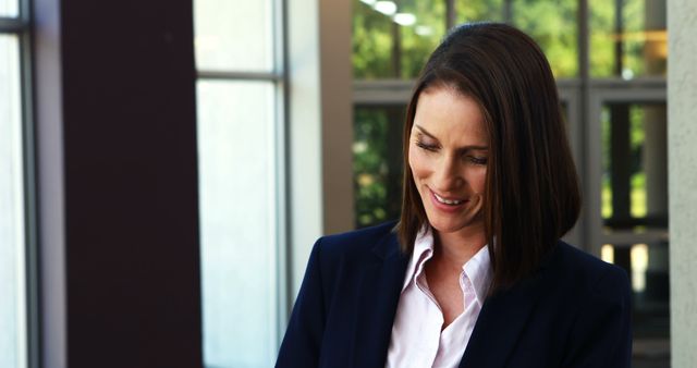 Smiling Businesswoman in Office Setting Next to Large Windows - Download Free Stock Images Pikwizard.com