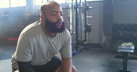 African american man resting on bench after weight set in gym for training recovery