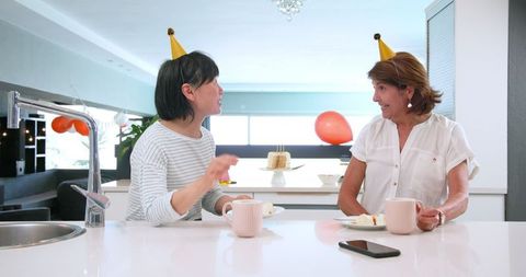 Senior women celebrating birthday with cake and coffee in kitchen