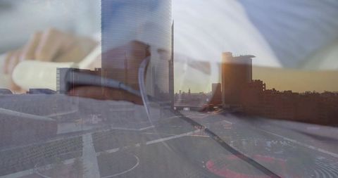 Typing hands working on laptop reflecting sunset skyline from office window, urban dusk