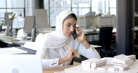Architectural Professional in Hijab Discussing Project on Smartphone