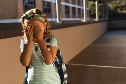 Young Student Playfully Covering Face on School Balcony