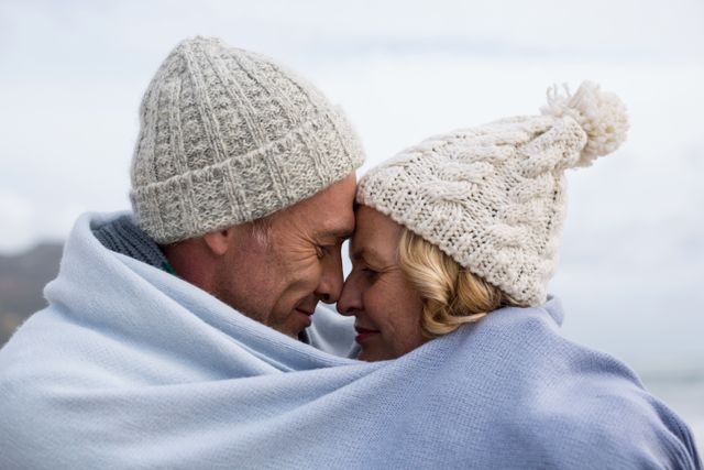 Mature couple wrapped in blanket on the beach - Download Free Stock Photos Pikwizard.com