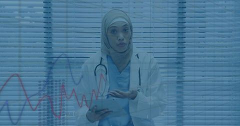 Hijab-Wearing Doctor Analyzing Medical Data on Tablet