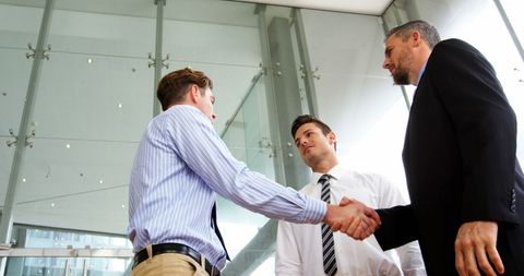 Businessmen Shaking Hands in Modern Office Atrium - Download Free Stock Images Pikwizard.com