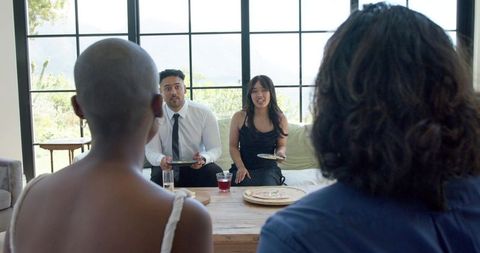 Young adults sharing flatbread and drinks during sunlit living room social gathering