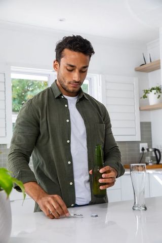 Man opening beer bottle in bright modern kitchen