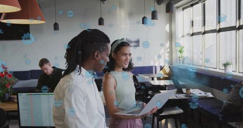 Diverse Professionals Reviewing Project on Laptop in Modern Office