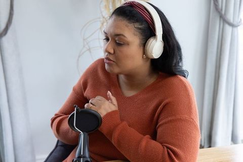 African american woman recording podcast at home wearing headphones rust sweater with microphone