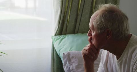 Senior Man Reflecting by Window at Retirement Home