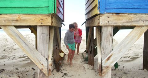 Children Playing Between Vibrant Beach Huts on Sandy Shore