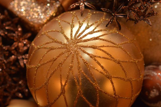 Gold glitter Christmas ornament with intricate design suitable for holiday greeting cards, festive backgrounds, seasonal advertisements, or Christmas decoration blogs.