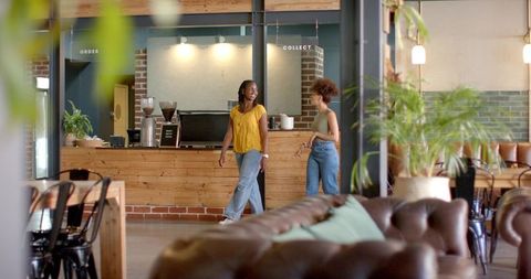 Two women chatting at modern coffee counter in stylish brick cafe