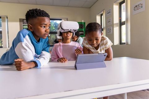 African american children exploring virtual reality and tablet learning in bright classroom