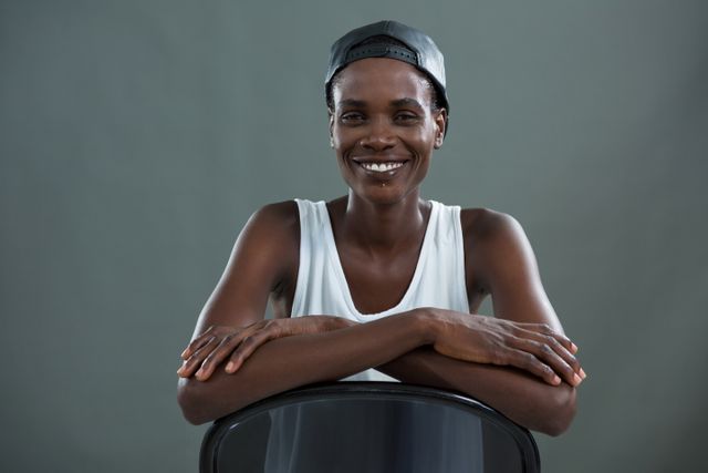 Androgynous man in cap smiling at camera against grey background