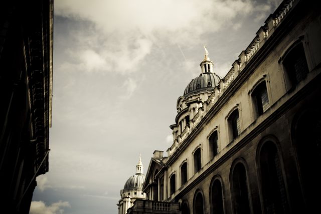 Depicting historic architectural domes under a cloudy sky, accentuated by a vintage filter. Ideal for projects focusing on classical architecture, urban landscapes, or for use in travel blogs and historical documentaries.