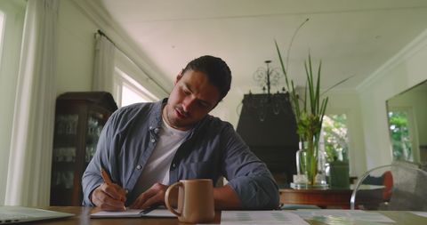 Freelancer writing notes in home office with coffee and laptop