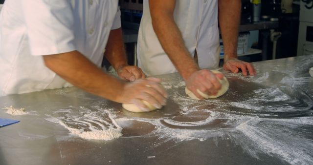 Bakers kneading dough on a metal countertop, preparing bread or pastries. Ideal for use in culinary blogs, restaurant websites, bakery promotions, professional cooking courses, and kitchen equipment advertisements.