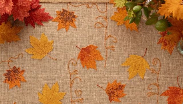 Burlap tablecloth featuring stitched orange vines and autumn leaves for fall decor