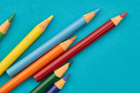 Vibrant sharpened colored pencils arranged diagonally on turquoise background