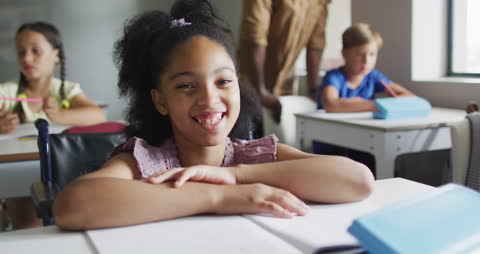 Happy Girl Smiling at Desk in Classroom Setting