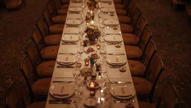 Long candlelit banquet table with elegant place settings, glassware and floral centerpieces