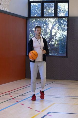 Confident Male Basketball Coach in Gym with Ball and Whistle
