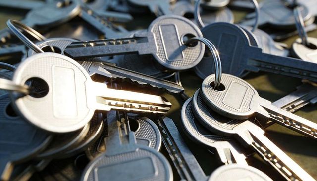 Cluster of silver house keys on key rings glinting with wear and texture
