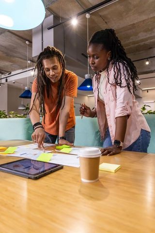 Diverse team collaborating and brainstorming over charts and tablet in coworking space