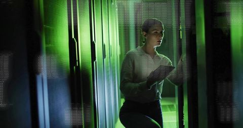 It technician beneath green server arrays in data center