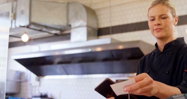 Female Chef Using Smartphone in Industrial Kitchen Looking at Note - Download Free Stock Images Pikwizard.com