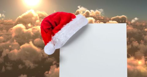 Santa Hat Above Blank White Card Against Cloudy Sky