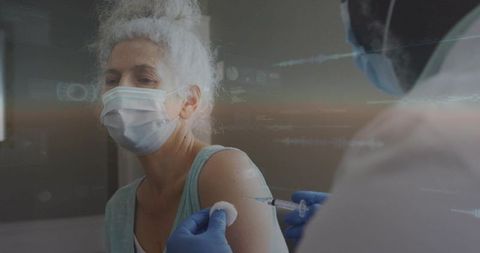 Senior woman receiving vaccine while masked nurse administering injection into upper arm