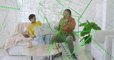 Collaborating friends using laptop and smartphone with green digital overlay in living room