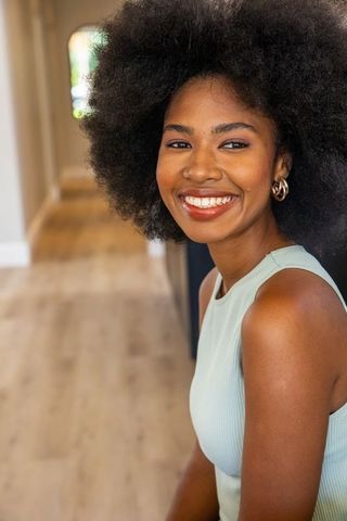 Smiling Woman with Afro Sitting in Stylish Home Interior
