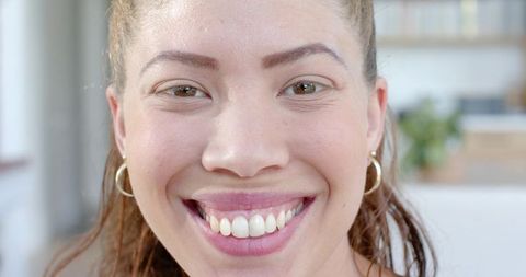 Close-up smiling woman wearing gold hoop earrings and natural makeup high-key headshot