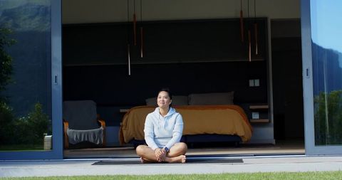 Woman practicing mindfulness on patio with open doors